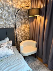 a bedroom with a chair and a lamp next to a bed at AbahHomeStudio Tunjung in Kota Bharu