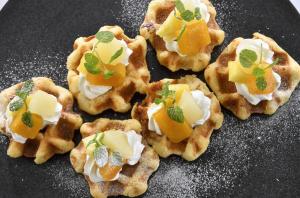 three waffles with fruit and cream on a black plate at Hotel Crown Palais Kitakyushu in Kitakyushu