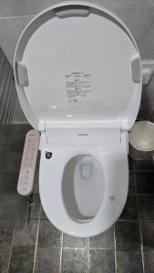 een wit toilet in een badkamer met afstandsbediening bij Wind Jeju Cafe & Pension in Seogwipo +32 foto's