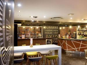 een restaurant met een bar met krukken eromheen bij Novotel Toulouse Purpan Aéroport in Toulouse