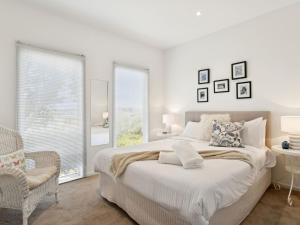 een witte slaapkamer met een groot bed en een stoel bij Olive Tree Retreat in Tootgarook