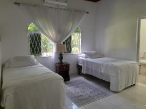 two beds in a room with two windows at Coco Gardens in Negril