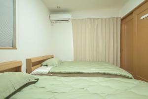 a bedroom with two beds and a window at Peace and Harmony House Rongsheng in Nagoya