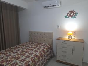 een slaapkamer met een bed en een dressoir met een lamp bij Studio Litorâneo para Relaxar in Governador Celso Ramos