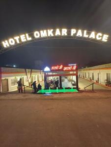 Personas de pie bajo un hotel que antaño era un palacio por la noche. en Hotel Omkar Palace, en Ayodhya