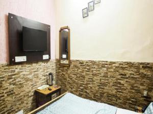 a room with a tv on a brick wall at Hotel Grand in Dehradun