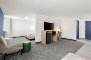 a room with a bed and a tv and a chair at Spark By Hilton Muskogee in Muskogee