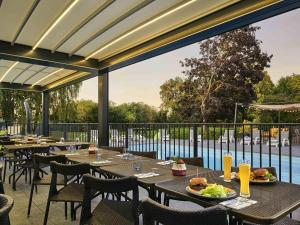 ein Restaurant mit Tischen und Stühlen und Poolblick in der Unterkunft Novotel Roissy Saint Witz in Saint-Witz