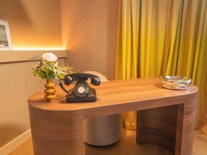 een bureau met een telefoon en een vaas met bloemen bij Pullman Toulouse in Blagnac