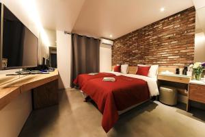 a bedroom with a red bed and a brick wall at The Lime Hotel in Incheon