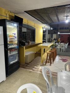 a kitchen with a refrigerator and tables and chairs at Dani Hostel e Pousada in Maceió