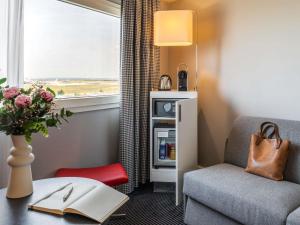 a room with a chair and a table and a window at Mercure Paris CDG Airport & Convention in Roissy-en-France +119 photos