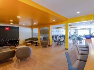 een lobby met stoelen en tafels en een groot scherm bij ibis Montélimar Nord in Saulce-sur-Rhône