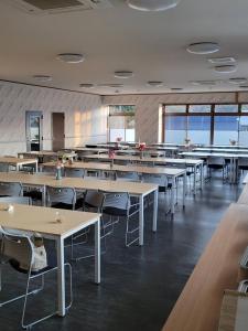 een eetkamer met tafels en stoelen en ramen bij ホテル富士山水館富士山一望河口湖車で3分HotelFujisanSuikanMtFujiView3 MinutesbyCartoLakeKawaguchi in Fujikawaguchiko