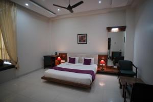 een slaapkamer met een bed, een bureau en een stoel bij Mount Valley Resort in Kumbhalgarh +18 foto's