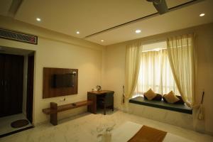een woonkamer met een bank, een tv en een raam bij Mount Valley Resort in Kumbhalgarh