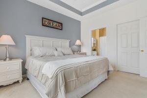 een witte slaapkamer met een bed en een bord aan de muur bij Stylish Barefoot Golf Condo with Pool Access in North Myrtle Beach