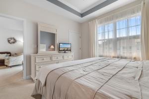 een witte slaapkamer met een groot bed en een raam bij Stylish Barefoot Golf Condo with Pool Access in North Myrtle Beach