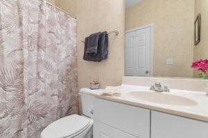 een badkamer met een wastafel, een toilet en een spiegel bij Stylish Barefoot Golf Condo with Pool Access in North Myrtle Beach