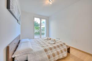 een witte slaapkamer met een bed en een raam bij Rebecca Garden - Happy Rentals in Lugano