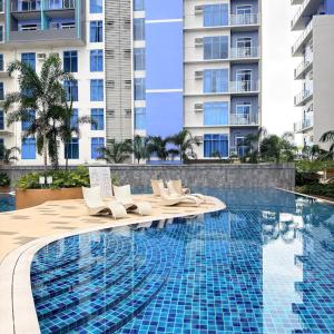 una piscina con sedie a sdraio accanto a un grande edificio di The Executive Suite Cebu a Cebu City