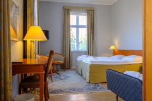 um quarto de hotel com duas camas, uma secretária e uma mesa em Zleep Hotel Prindsen Roskilde em Roskilde
