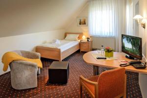 リップシュタットにあるHotel-Pension Pöhlingのベッドとデスクが備わるホテルルームです。
