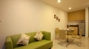 een woonkamer met een groene bank en een keuken bij Landmark Residence in Ban Khlong Sanam Phli