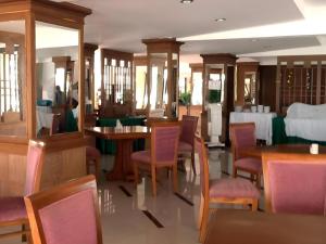 una sala da pranzo con tavoli e sedie in legno e un tavolo di PC Palace Hotel a Sakon Nakhon