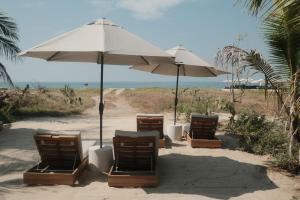 a group of chairs and umbrellas on a beach at Notto Zicatela Hotel in Puerto Escondido
