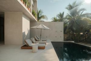 a swimming pool with two lounge chairs and an umbrella at Notto Zicatela Hotel in Puerto Escondido