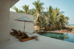 een zwembad met ligstoelen en een parasol bij Notto Zicatela Hotel in Brisas de Zicatela