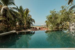 een zwembad met palmbomen en de oceaan bij Notto Zicatela Hotel in Brisas de Zicatela +40 foto's