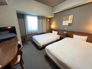 a hotel room with two beds and a television at Hotel Route-Inn Sakaide-Kita Inter in Sakaide