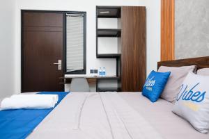 una camera da letto con un letto con cuscini blu e bianchi di Vibes Djanti Residence Yogyakarta By Sans Hotel a Demangan Altre 85 foto