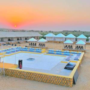 uma piscina com mesas e guarda-sóis numa praia em Royal Sand Desert Resort em Sām