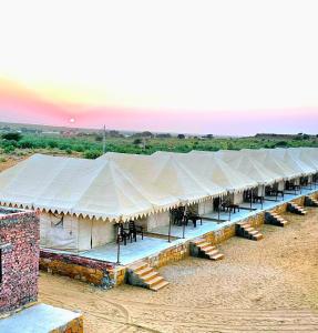 uma grande tenda com mesas e cadeiras num campo em Royal Sand Desert Resort em Sām