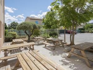 a group of wooden picnic tables in a parking lot at B&B HOTEL Brignoles in Brignoles