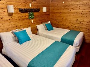 twee bedden in een kamer met houten wanden bij アジアンウッドコテージ in Motobu