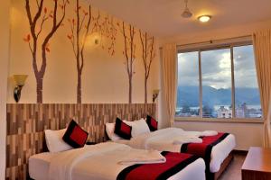2 letti in una stanza con alberi sul muro di Hotel City Inn - Mountain View a Pokhara Altre 37 foto