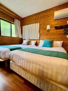 twee bedden in een kamer met houten wanden bij アジアンウッドコテージ in Motobu