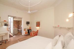 Habitación blanca con cama y escritorio en Motel Mi Pi Chi, en Johannesburgo