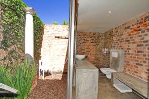 a bathroom with a toilet and a brick wall at Motel Mi Pi Chi in Johannesburg