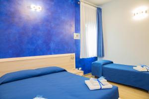 1 dormitorio con 2 camas y pared azul en SONRE' B&B, en Ruffano