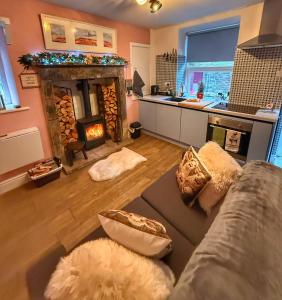 een woonkamer met een bank en een open haard bij Orchard Nook Cottage in Barnoldswick