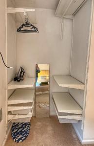 a walk in closet with white shelves and a mirror at Orchard Nook Cottage, 1 bedroom in Barnoldswick +2 photos