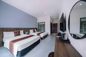een hotelkamer met twee bedden en een spiegel bij V Fleurs Hotel Cat Ba in Cat Ba