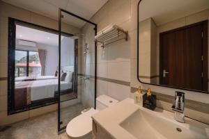 een badkamer met een wastafel, een toilet en een spiegel bij Véra Stay - Cat Ba in Cat Ba