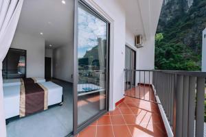 een slaapkamer met een balkon met een bed en uitzicht bij V Fleurs Hotel Cat Ba in Cat Ba