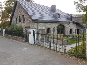 uma velha casa de pedra com uma cerca preta em La Ferme de Spa em Spa